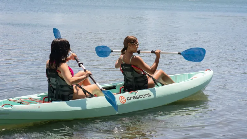 Couple paddling a stable tandem double kayak across the Condado Lagoon kayak nature reserve with the San Juan skyline behind, Puerto Rico