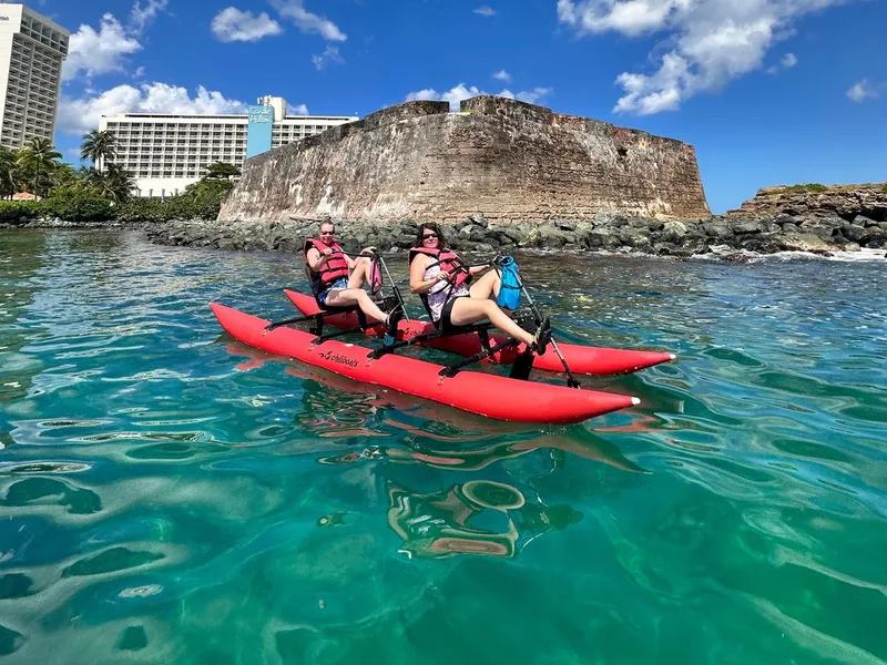 Visitor pedaling a stable Chiliboats water bike across the calm Condado Lagoon near the kayak launch with San Juan skyline views, Puerto Rico