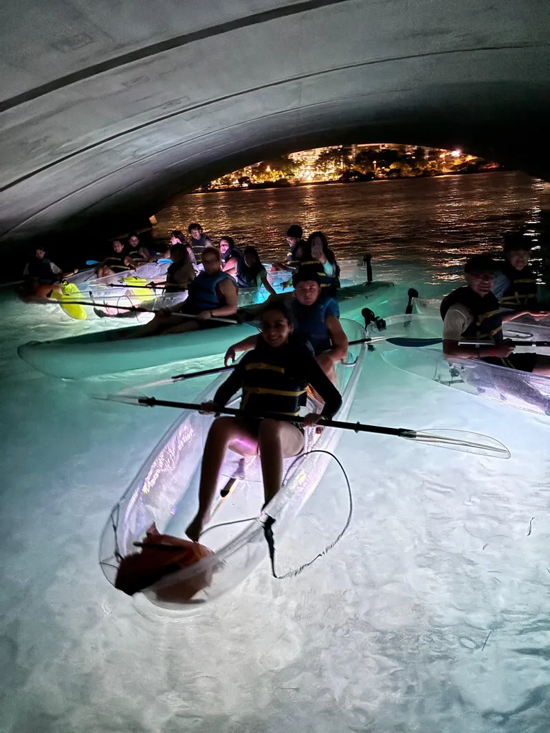 Transparent LED-lit clear kayak glowing on the dark water during a night led kayak tour on the Condado Lagoon in San Juan, Puerto Rico