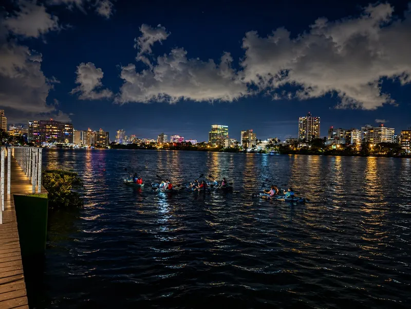 Clear kayak on the dark Condado Lagoon with the glowing San Juan city skyline behind on a night kayak skyline tour, Puerto Rico
